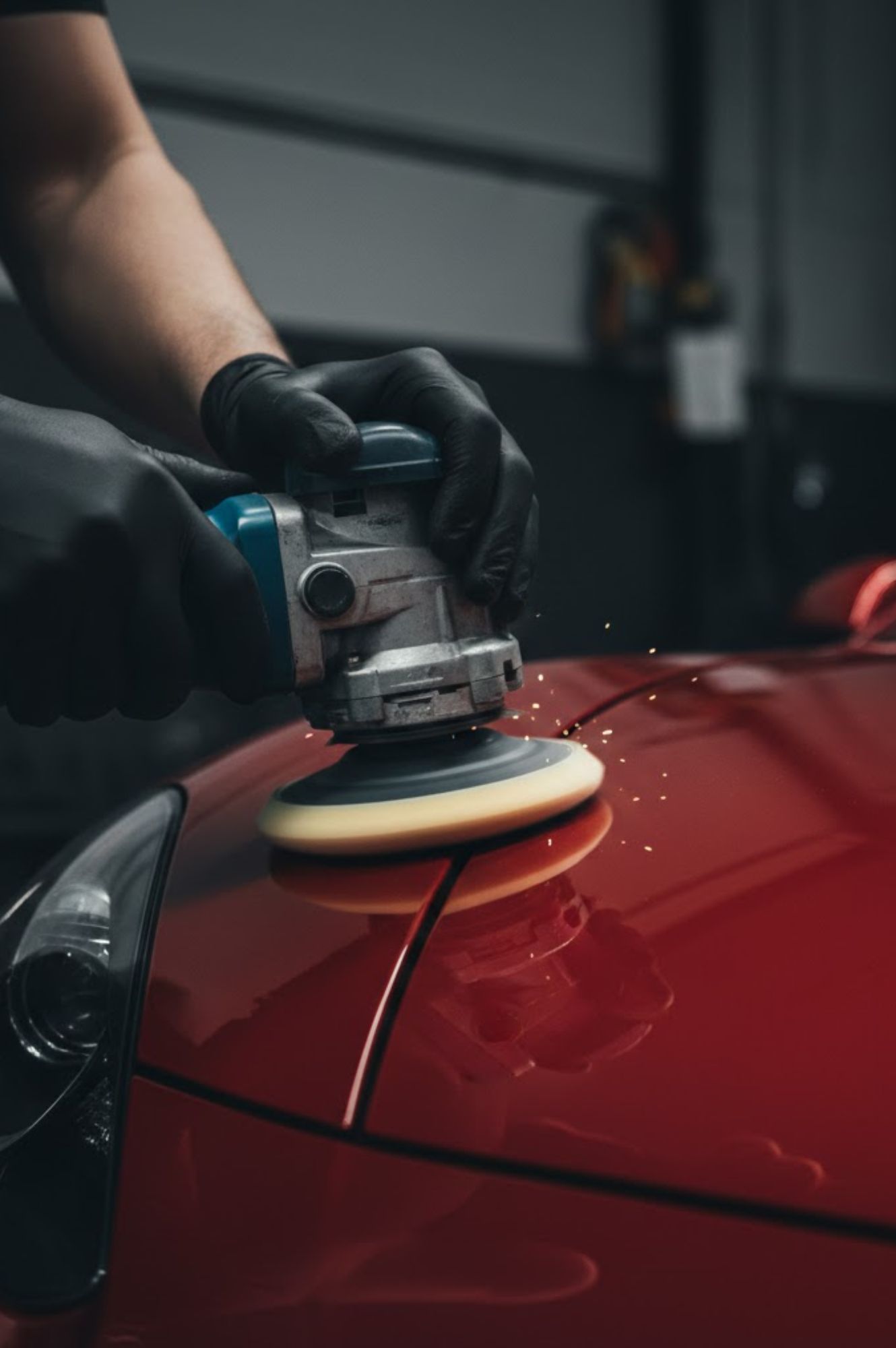 Pulido de carrocería de automóvil rojo con pulidora eléctrica en taller